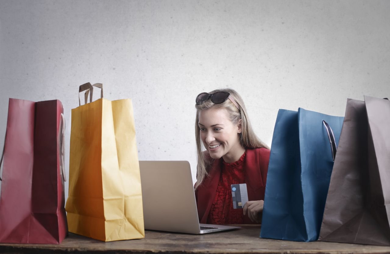 The Art of Drawing Readers In: Your attractive post title goes here Cheerful young female with credit card in hand using laptop and enjoying shopping online while sitting at table with various colorful shopping bags