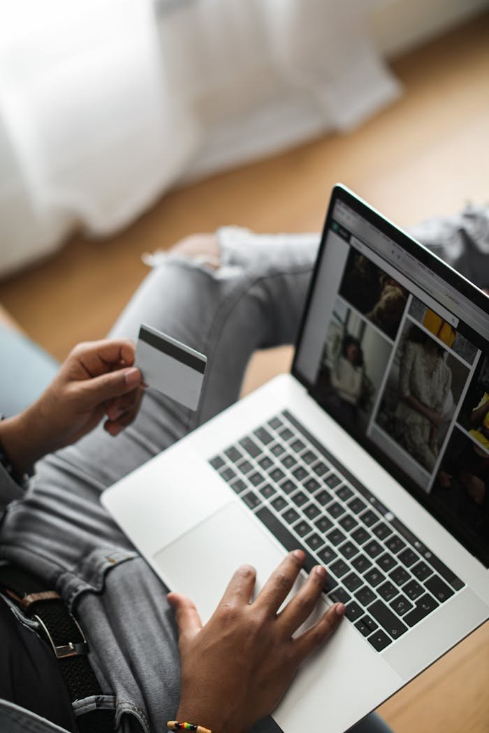 Mastering the First Impression: Your intriguing post title goes here Person using credit card for online shopping on laptop in relaxed setting.